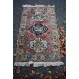 A Persian rug, having three central medallions on a pink field with geometric borders, 160 x 90cm.