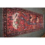 An Eastern rug, having animal motifs on a red field, with floral borders, 320 x 127cm.