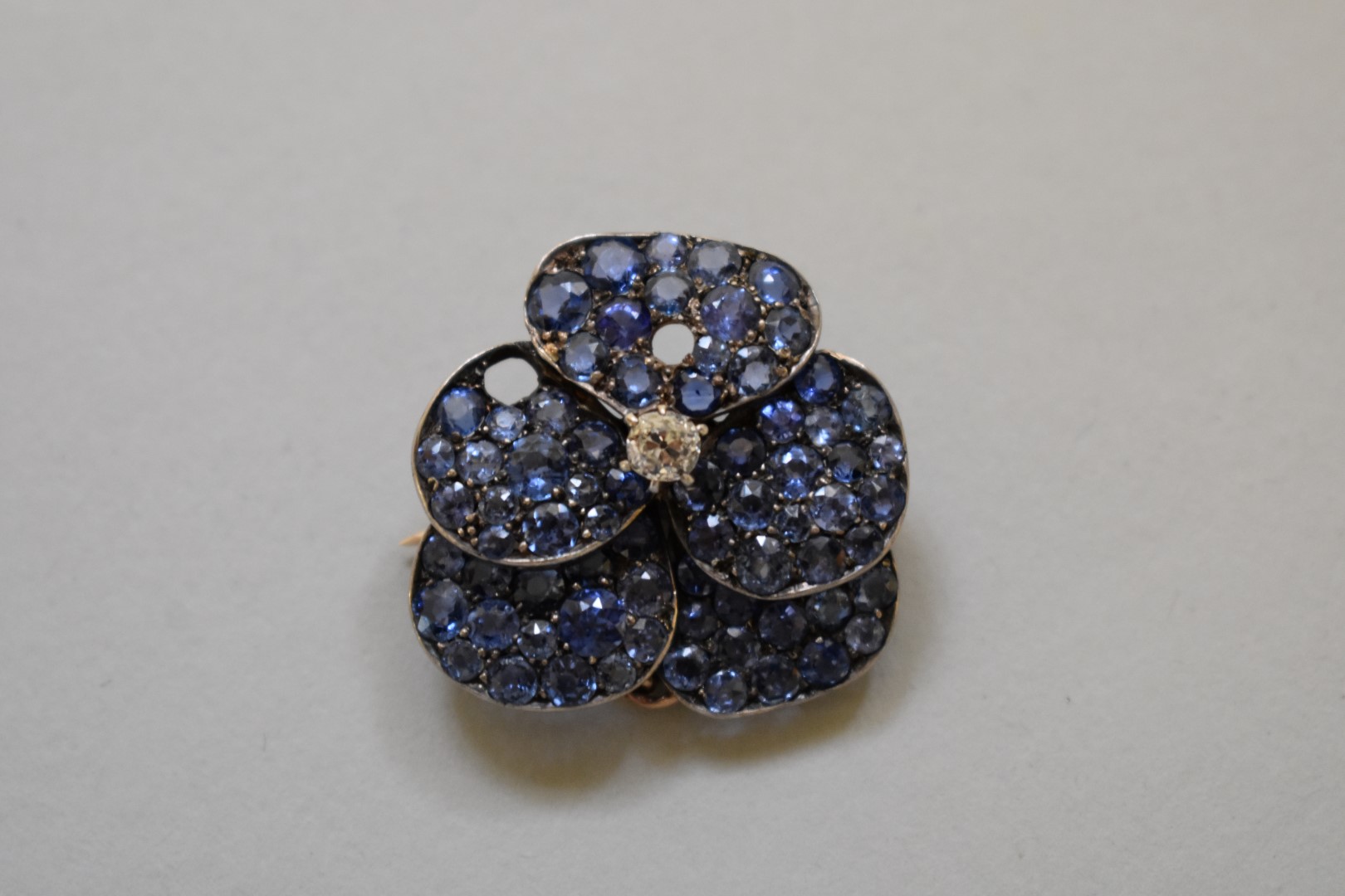 A sapphire and diamond encrusted 'pansy' pendant brooch, set in unmarked yellow metal, 27mm, 9.6g