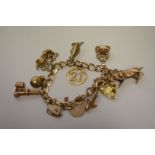 A gold charm bracelet, hallmarked 375, having eleven charms attached, six hallmarked 375, one