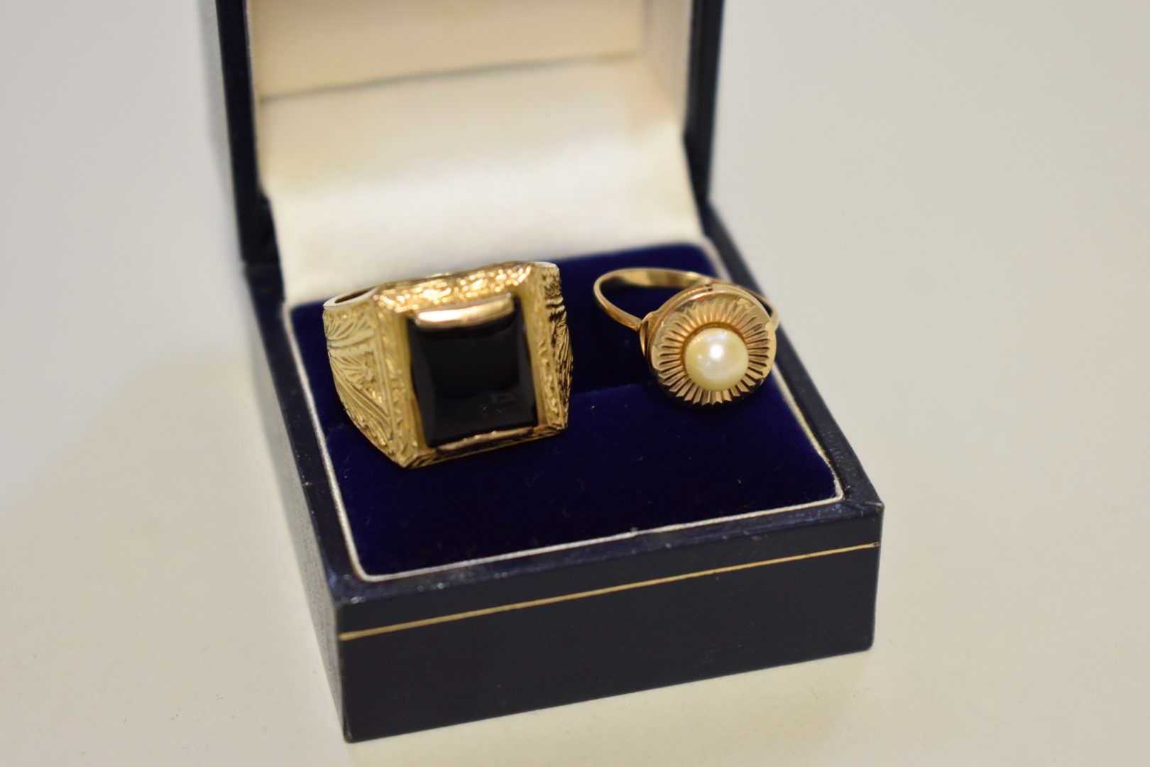 An onyx unmarked yellow metal gentleman's ring; together with an unmarked yellow metal pearl ring,