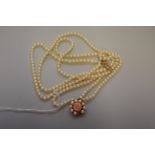 A triple strand pearl choker, having pearl and carved coral clasp, 35.5cm long, 29.5g total weight.