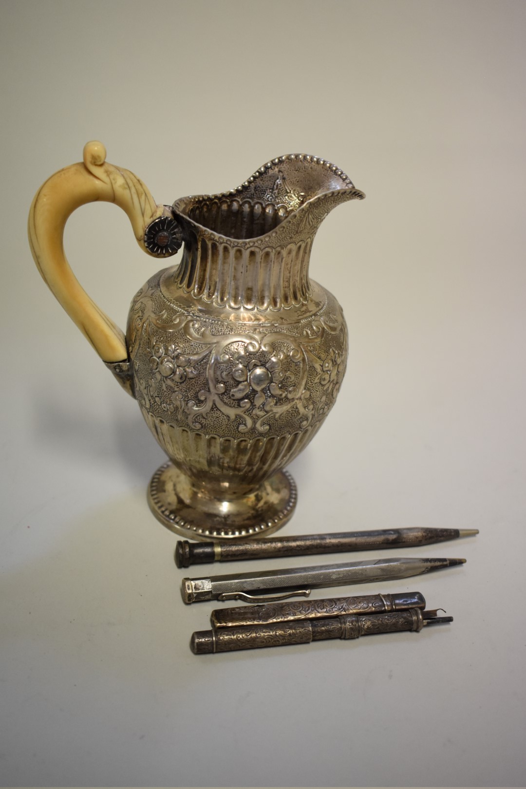 A Continental white metal ivory handled ewer; together with two silver pencils; a Morden & Co