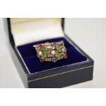 A five strand gem set unmarked yellow metal ring, studded sapphires, rubies, peridots, diamonds