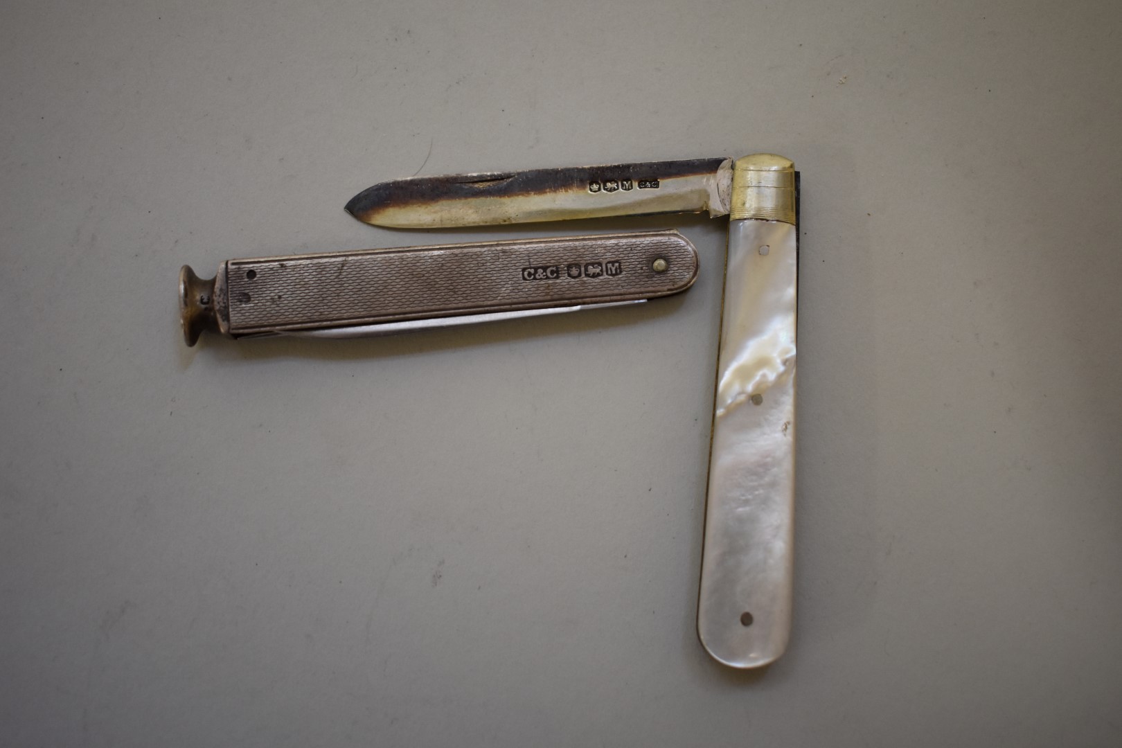 A silver engine turned smokers knife; together with a silver bladed mother of pearl penknife. (2)