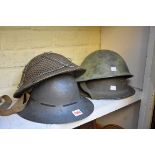 Four various military tin helmets.