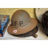 Two old tin helmets, one inscribed 'SFP'.