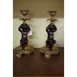 A pair of bronze cherub candlesticks, 21cm high.