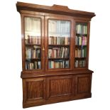 A GOOD VICTORIAN MAHOGANY TRIPLE BOOKCASE With stepped cornice above three glazed doors and panelled