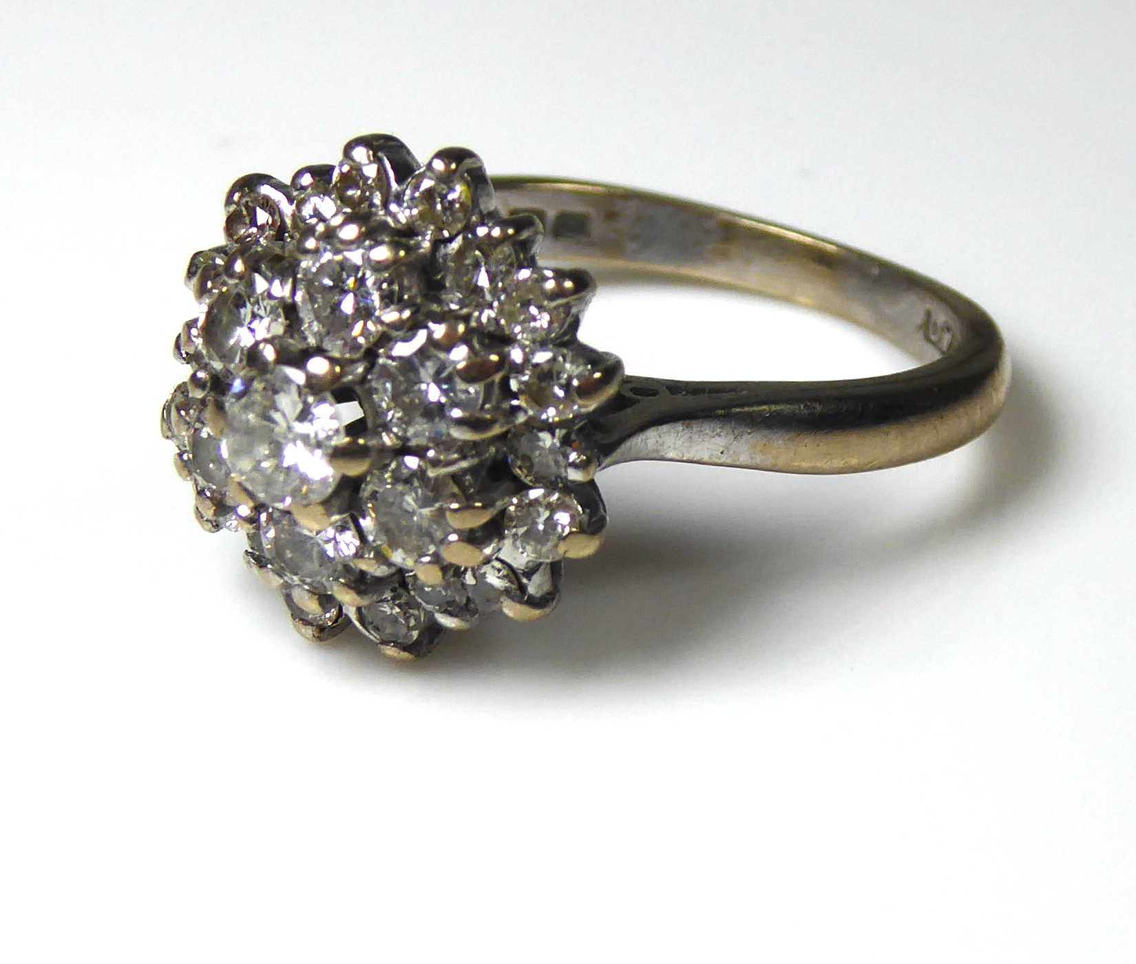 A VINTAGE 18CT WHITE GOLD AND DIAMOND CLUSTER RING The central round cut diamond surrounded by two