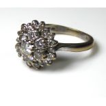 A VINTAGE 18CT WHITE GOLD AND DIAMOND CLUSTER RING The central round cut diamond surrounded by two
