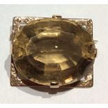 AN EARLY 20TH CENTURY 9CT GOLD AND CITRINE BROOCH The oval cut faceted stove, held in an engraved