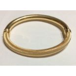 A VINTAGE 18CT GOLD BRACELET Oval form with textured decoration and a hinged clasp. (approx 7cm)