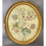 A 19TH CENTURY SILK EMBROIDERY Flowers and foliage in and gilt oval frame, labelled verso.