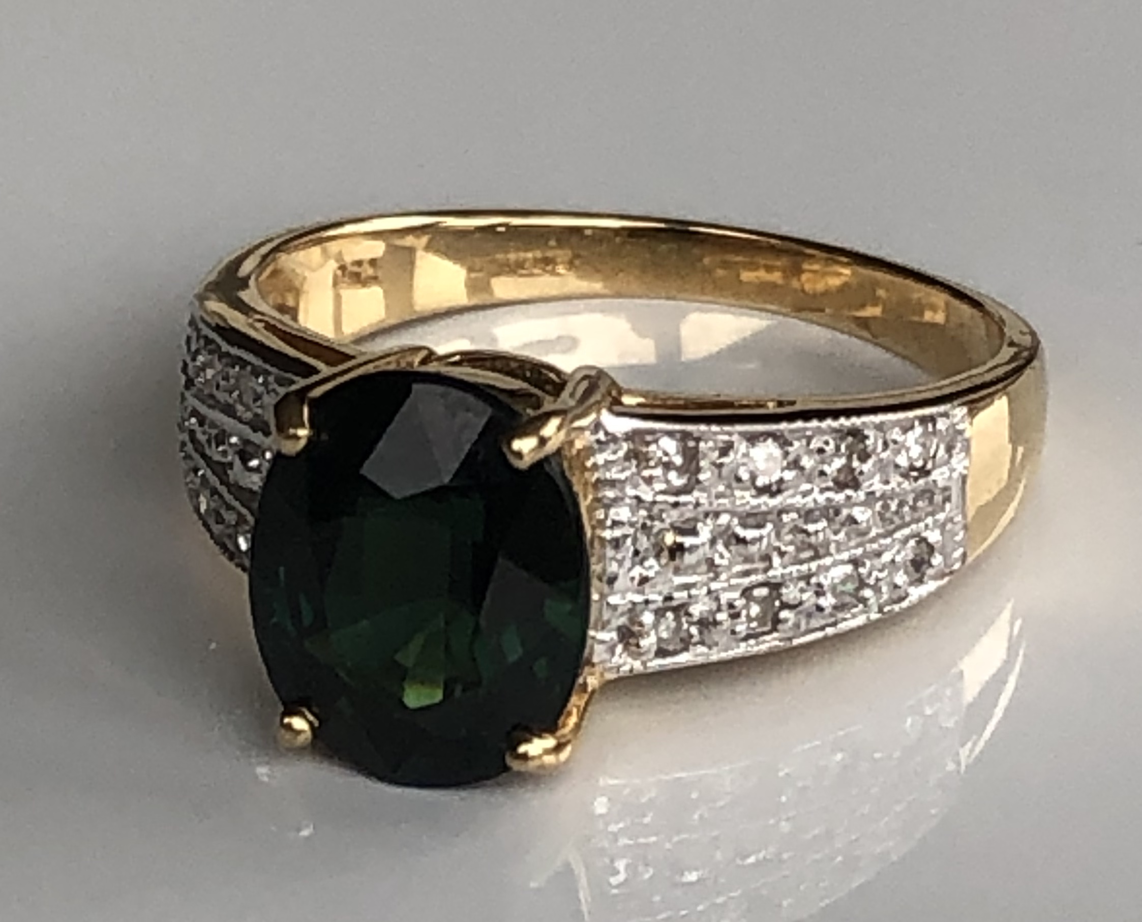 AN 18CT GOLD, INDICOLITE AND DIAMOND RING The oval cut indicolite on diamond shoulders (size O).