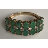 A 9CT GOLD, EMERALD AND DIAMOND RING Having an arrangement of fourteen oval cut emeralds, set in two