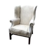 A GEORGIAN DESIGN WING ARMCHAIR Upholstered in a pale green floral fabric and feather filled loose