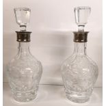 A PAIR OF SILVER AND CUT CRYSTAL GLASS DECANTERS Having octagonal form stoppers and plain silver