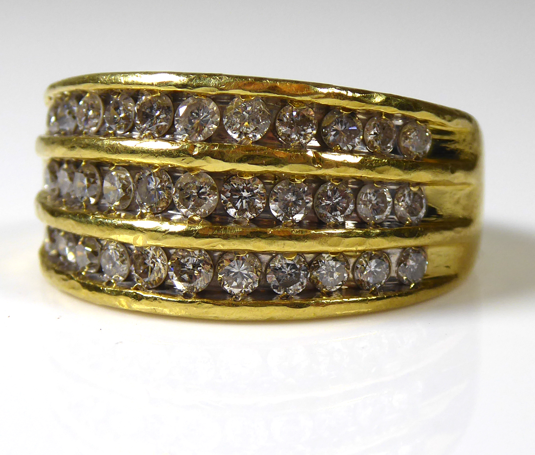 AN 18CT GOLD AND DIAMOND RING Three rows of round cut diamonds on a plain gold band (size O). (