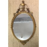 A REGENCY STYLE GILT FRAMED MIRROR With urn a swags above an oval plate. (54cm x 99cm)