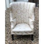 AN EDWARDIAN WING ARMCHAIR In an ivory frontal fabric, raised on square tapering legs. (80cm x