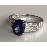 AN 18CT GOLD, TANZANITE AND DIAMOND RING The oval cut tanzanite on diamond shoulders (size N/O).