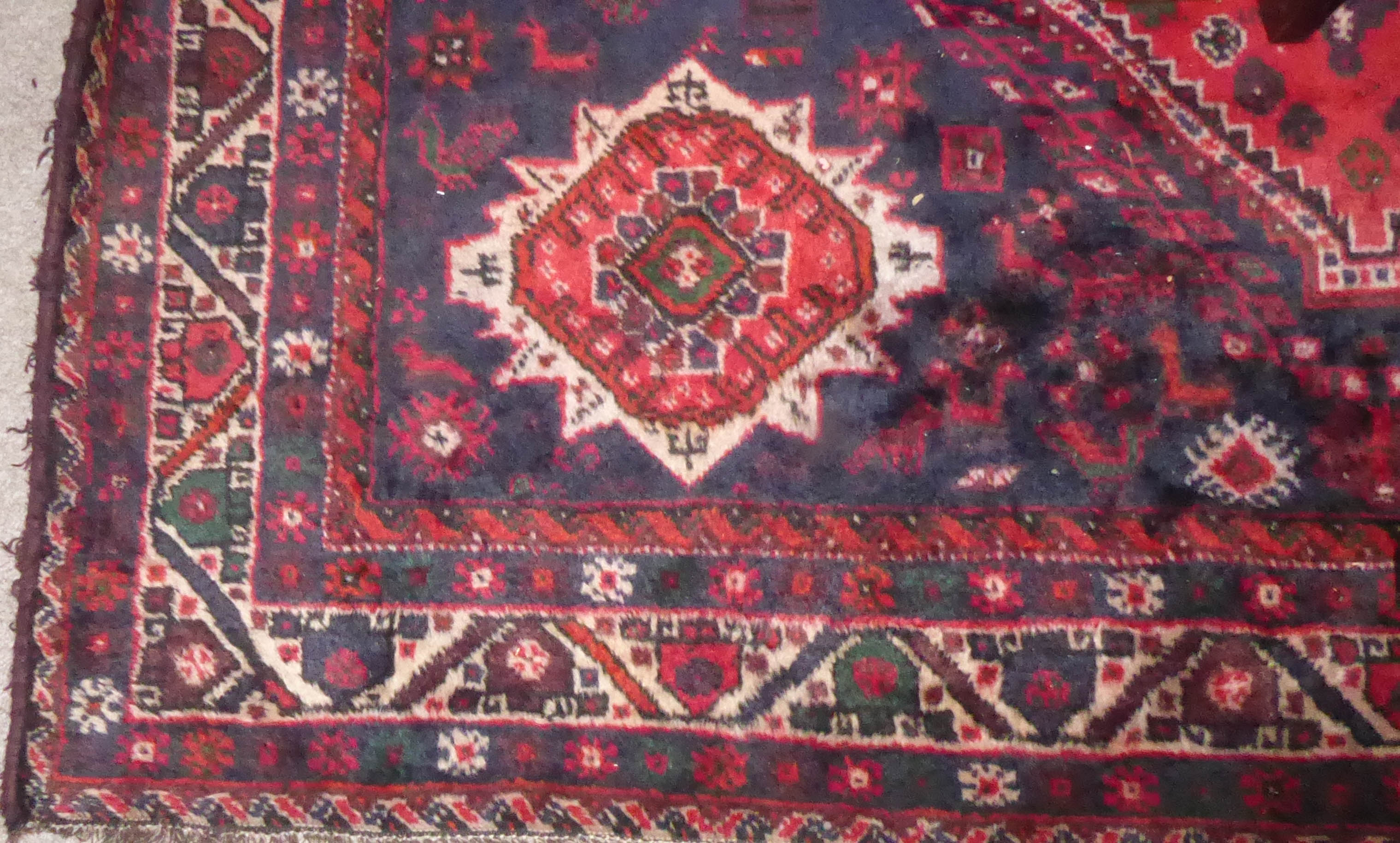 AN ANTIQUE WOOLLEN RUG The central medallion flanked by four guls and zoomorphic motifs within three