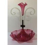 A VICTORIAN CRANBERRY GLASS EPERGNE Having a central trumpet form flute, with scrolled glass canes