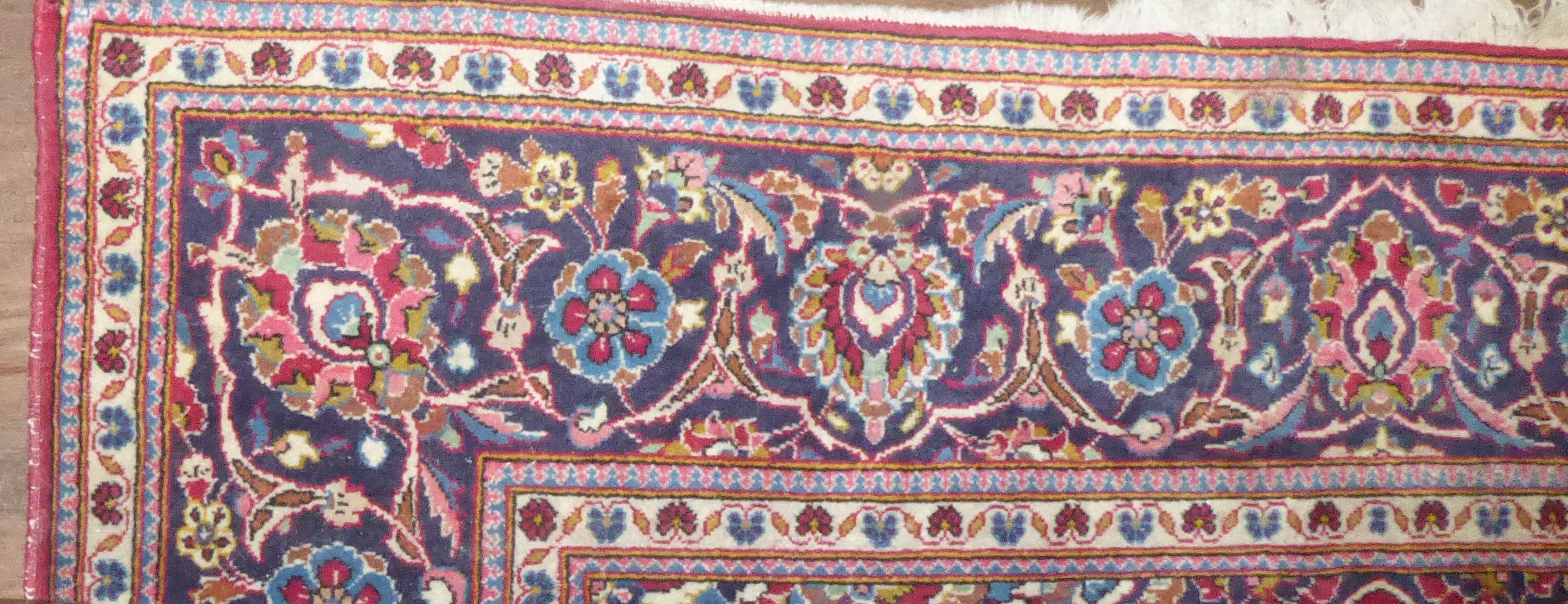 A PERSIAN DESIGN WOOLLEN RUG The madder field with pendant medallion and floral decoration within