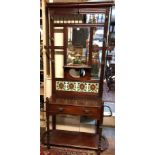 AN EARLY 20TH CENTURY MAHOGANY HALL STAND The back with bevelled edge mirror, foliate painted tiles,