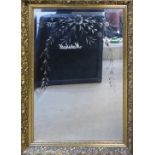 A 20TH CENTURY BEVELLED GLASS RECTANGULAR MIRROR With etched decoration, in a carved gilt frame. (