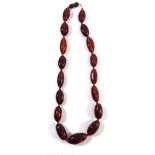 AN AMBER BEAD NECKLACE Having oval form graduating beads. (approx 24cm)