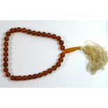 A VINTAGE AMBER BEAD NECKLACE The single strand of spherical beads with silk tassel. (approx 22cm)