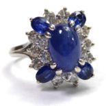 A 14CT WHITE GOLD RING Set with a central cabochon sapphire surrounded by sapphires and diamonds.