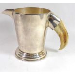 PHV & CO., A 20TH CENTURY WHITE METAL PITCHER The tapering form body having a boars tusk handle,