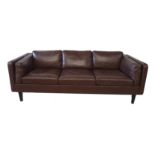 HEALS OF LONDON, A BROWN LEATHER THREE SEAT SETTEE Complete with loose cushions, raised on square