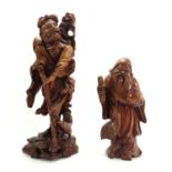 TWO 20TH CENTURY CARVED WOODEN FIGURES An elder with a large peach and bird and a figure clutching a