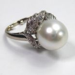 A 14CT WHITE GOLD DRESS RING Set with a large central pearl surrounded by baguette and brilliant cut