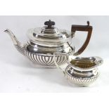 AN EARLY 20TH CENTURY SILVER BATCHELOR'S TEAPOT AND CREAM JUG Having a half fluted body and wooden