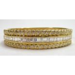 AN 18CT GOLD BANGLE Set with 4.83ct baguette and 1.61 brilliant cut diamonds. (47g)