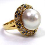 A YELLOW METAL COCKTAIL RING Set with a large pearl surrounded by diamonds and sapphires.