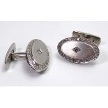 A PAIR OF OVAL FORM WHITE METAL AND DIAMOND CUFFLINKS. (16.9g
