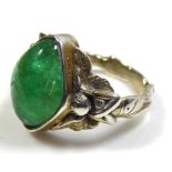 A CONTINENTAL WHITE METAL AND EMERALD RING The cabochon cut stone held in a figural mount, with