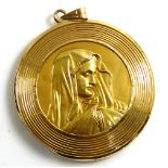 A VINTAGE YELLOW METAL RELIGIOUS PENDANT The circular form embossed with a portrait of Mary, clasp