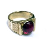 AN EARLY 20TH CENTURY YELLOW METAL AND RUBY RING Cabochon cut ruby collet set in a square mount with