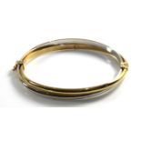 A 9CT BICOLOUR GOLD BANGLE Two entwined gold bands on a single clasp. (approx 7cm)