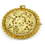 AN INDIAN YELLOW METAL AND IVORY BROOCH Finely carved with fish with a floral bouquet, held in a