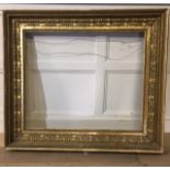 A 19TH CENTURY CARVED GILTWOOD AND GESSO PICTURE FRAME Having a leaf and scroll border with beaded