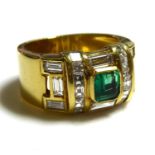 A HEAVY 18CT GOLD RING SET WITH A CENTRAL EMERALD SURROUNDED BY BAGUETTE CUT DIAMONDS (size N/O). (