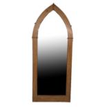 A LARGE VICTORIAN WAXED PINE FRAMED MIRROR IN THE FORM OF A GOTHIC ARCH With later peach glass